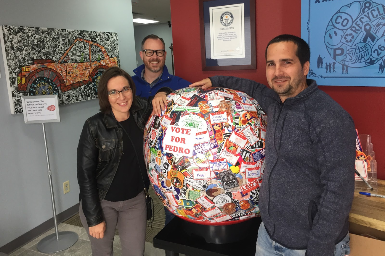 Employees from Bluespark stand next to the world's largest sticker ball